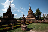 Thailand, Old Sukhothai - Wat Sa Si. Secondary chedi and main chedi with in front the Sukhothai style statue of  walking Buddha in the vitarka mudra. 